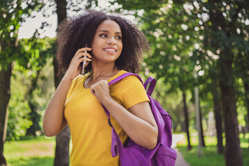 Portrait of attractive cheerful wavy-haired girl talking on phone strolling on fresh air sunny day at forest outdoor