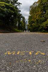 Obraz premium Long concrete path with meta sign in Citadel park with trees and lamps around