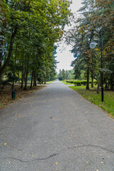 Fototapeta na wymiar Long concrete path in Citadel park with trees and lamps around