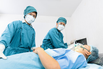 assistant surgeon put the patient on a ventilator-oxygen mask in preparation for surgery.