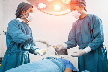 Assistant Hands out Instruments to Surgeons During Operation. Surgery and emergency concept