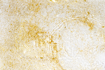 Golden sparkles in water. Gold glitter and liquide texture. Abstract background with golden particles. Shining celebration background. Festive backdrop for your projects.
