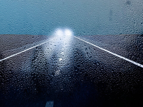 Regennasse Strasse und Gegenverkehr mit Scheinwerferlicht