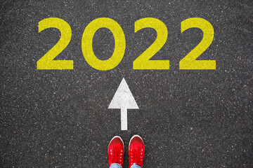 Obraz na płótnie Canvas Red sneakers on the asphalt road with 2022. Concept for success in the future goal and passing time. Happy new year concept