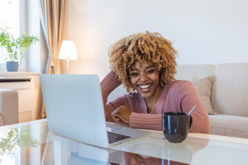 Fototapeta premium Image of young pleased happy cheerful cute beautiful business woman sit indoors at home using laptop computer. Beautiful young woman working on her laptop in her office.