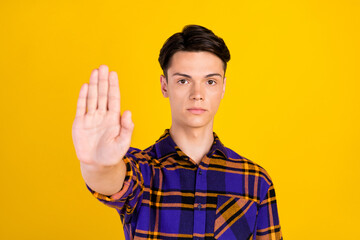 Photo of strict brunet millennial guy show stop wear checkered shirt isolated on yellow color background