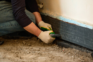 Installing waterproofing in a private home on the floor, a man attaches a waterproof tape to the...