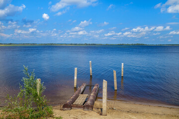 Remains of a river pier at the coast. In the background there is a panorama of the majestic Volga River. Classic view for the middle Volga region in Russia