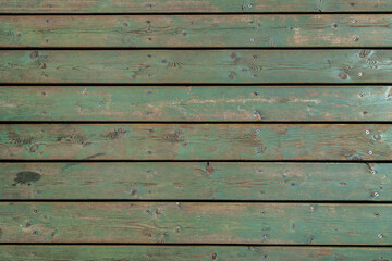 Obraz premium Wooden covering of the pedestrian street. The green color of the boards faded under the sun and weather. The boards are fixed with screws