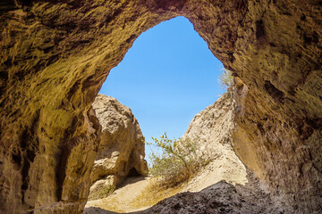 View of bright summer day and blue sky from darkness of cave. This is entrance to underground...