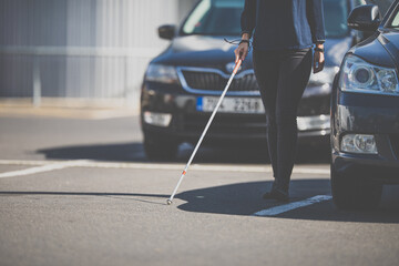 Blind woman walking on city streets, using her white cane to navigate the urban space better and to get to her destination safely