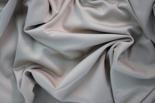 Draped canvas close-up. Abstract polyester fabric background. Top view of fabric with many folds. waves of satin material, shiny texture.