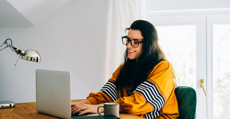 Smiling woman in her home office have video call on computer. Female freelance employee and work...