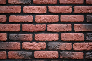 Red brick wall with black seams background. Decorative wall with brown tiles and black cement. Brick wall texture close-up.