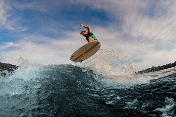 beautiful view of man flying in the air on wakesurf over splashing wave