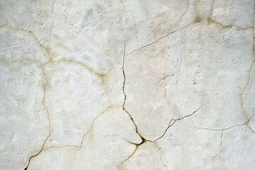 White wall with cracks close-up. Wall texture of an old building. Stone wall with cracks on the background surface.