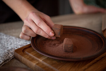 Naked women's Hands  keep chocolate candy. Brown dish with truffles. Copy space. Close-up.