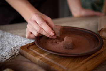 Naked women's Hands  keep chocolate candy. Brown dish with truffles. Copy space. Close-up.