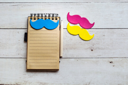 Happy Father's Day Card with empty notebook and Moustaches  on a  Wooden Background
