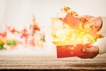Open gift box with golden magic light coming out against Christmas lights background. - obrazy, fototapety, plakaty