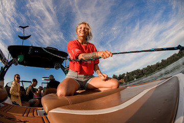 close-up of a smiling woman sitting on a boat and holding a wakesurf rope