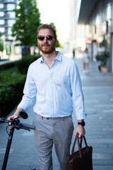 Young stylish businessman with e-scooter. Portrait of handsome man outdoors.