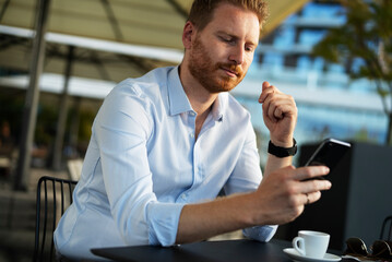 Handsome businessman drinking coffee in cafe. Young man enjoying in fresh coffee.