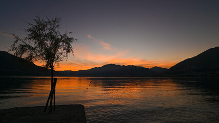 Magnifico tramonto sul lago, con cielo colorato di arancione, rosso, rosa