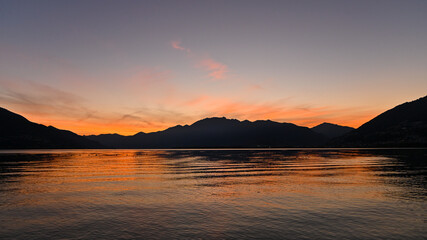 Naklejka na ściany i meble Magnifico tramonto sul lago, con cielo colorato di arancione, rosso, rosa