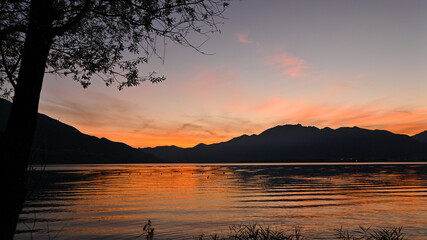 Magnifico tramonto sul lago, con cielo colorato di arancione, rosso, rosa © fotonaturali