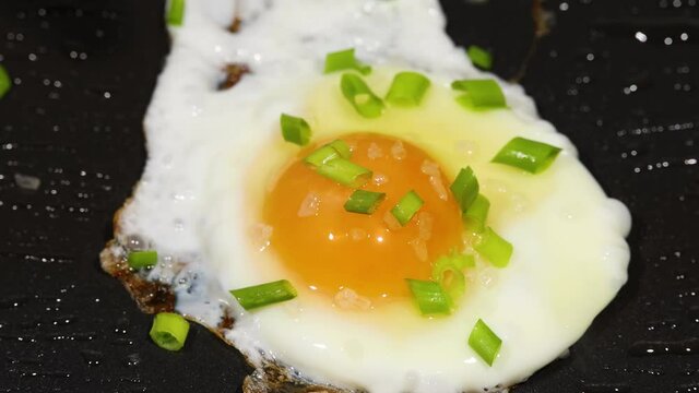 Sprinkling green scallion on sunny side up eggs p2