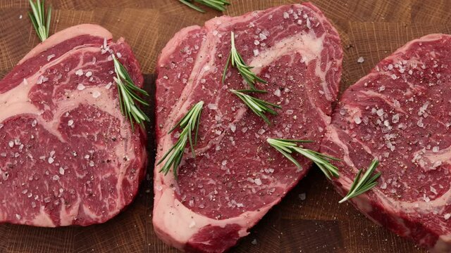 Seasoning raw ribeye beef steaks with rosemary p2