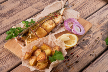 Composition smoked mackerel fish with garnish potatoes lemon greens onions served on wooden board plate top view