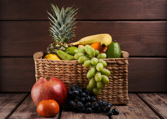 Mix of fresh juicy colorful exotic tropical fruits in basket on wooden background