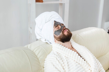 Bearded man has clean fresh skin, wears beauty clay mask on face and enjoys beauty treatments. Spa at home, body and skin care