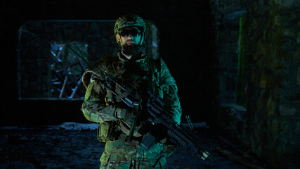 Portrait of airsoft player in professional equipment with machine gun in abandoned ruined building. Soldier with weapons at war