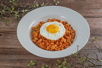 Korean food kimchi fried rice dish with fried egg on white plate