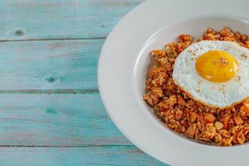 Korean food kimchi fried rice dish with fried egg on white plate