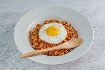 Korean food kimchi fried rice dish with fried egg on white plate