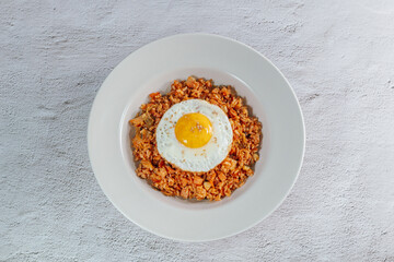 Korean food kimchi fried rice dish with fried egg on white plate
