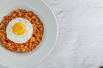 Korean food kimchi fried rice dish with fried egg on white plate