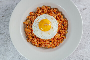 Korean food kimchi fried rice dish with fried egg on white plate
