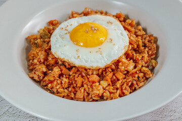 Korean food kimchi fried rice dish with fried egg on white plate