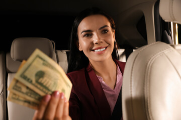 Young woman with money in modern taxi
