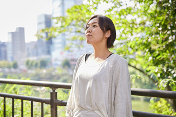 早朝の新緑の中でほほ笑む40代日本人女性