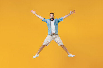 Fototapeta na wymiar Full body young smiling happy caucasian man 20s wearing blue shirt white t-shirt jump high with outstretched hands scream isolated on plain yellow background studio portrait. People lifestyle concept.