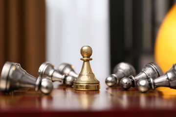 Pawn piece among defeated ones on chessboard indoors
