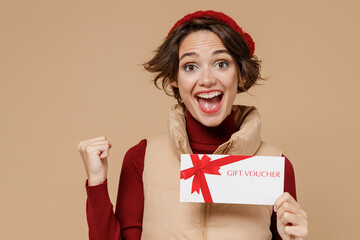 Young smiling happy fun woman 20s wearing red turtleneck vest beret hold gift certificate coupon...