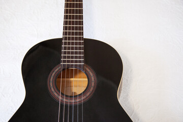 Guitarra española negra. Guitarra apoyada en cama. Fondo de guitarra española. Instrumento de cuerda. 