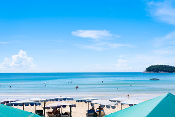 Fototapeta na wymiar umbrellas siting clean sea. Coconut trees on beach and white clouds blue sky.